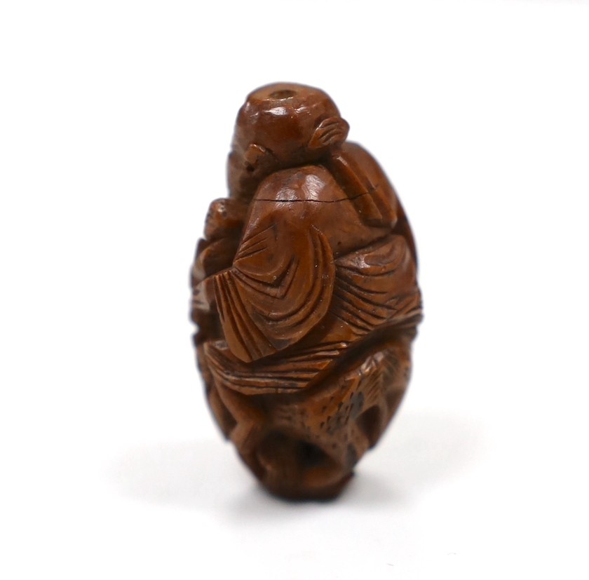 Five Chinese peach stone carvings, largest 4.2cm and a coquilla nut egg shaped box
